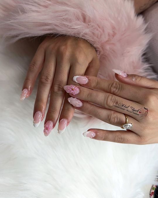 Pink almond nails with white French tips and floral accents against a fluffy pink cuff